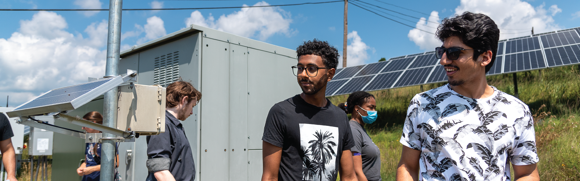 students smiling outside in solar panel field
